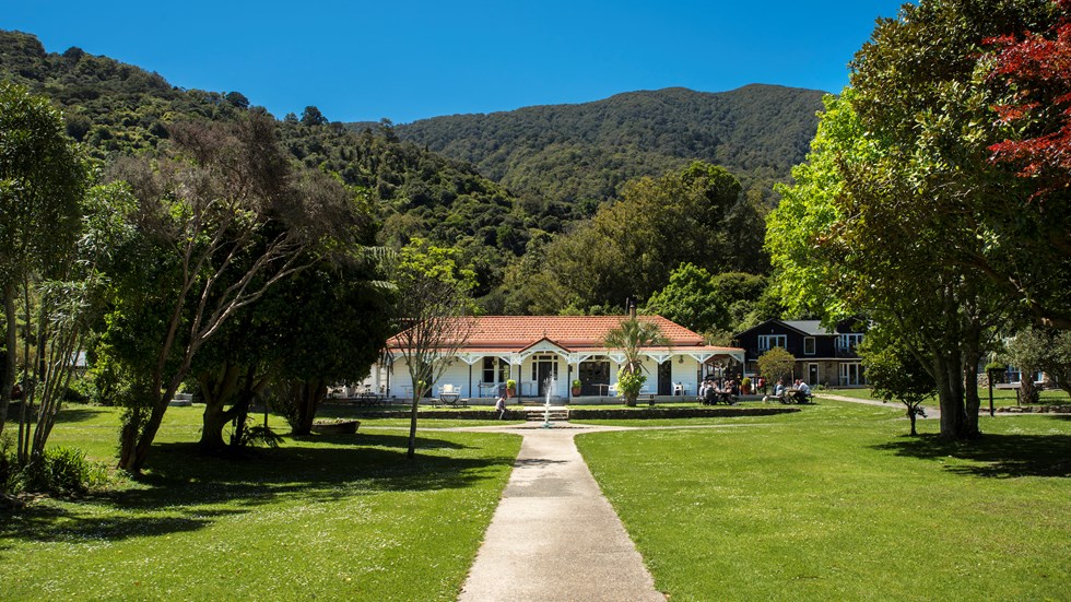 Large sweeping lawns and the front of historic Howden House with its distinctive verandah and orange tiled roof, in the Marlborough Sounds at the top of New Zealand's South Island.