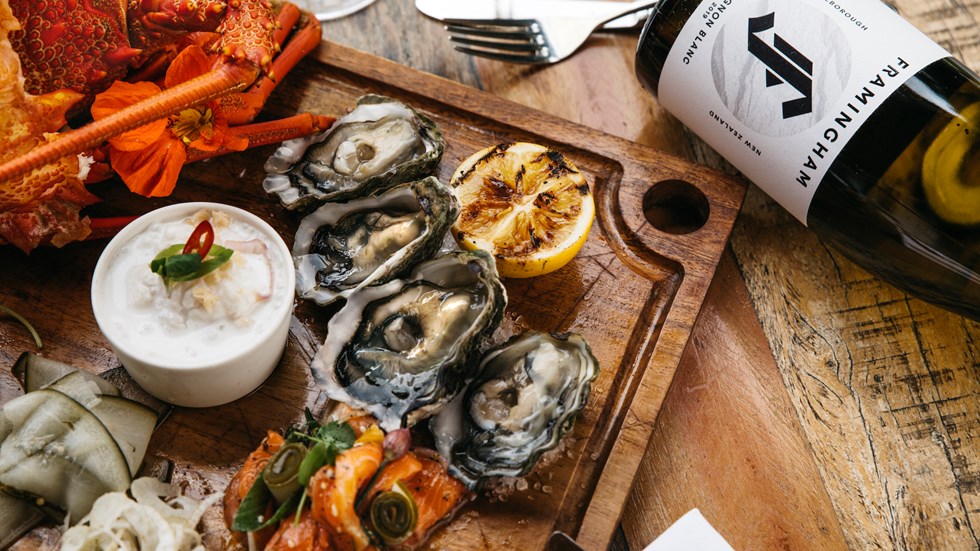 Delicious platter with oysters, crayfish, grilled vegetables paired with Framingham Sauvignon Blanc at the Furneaux Lodge Restaurant in the Marlborough Sounds at the top of New Zealand's South Island.