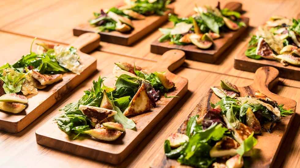 Honey drizzled fig and halloumi salad small plate dishes on wooden chopping boards at the Furneaux Lodge Restaurant in the Marlborough Sounds at the top of New Zealand's South Island