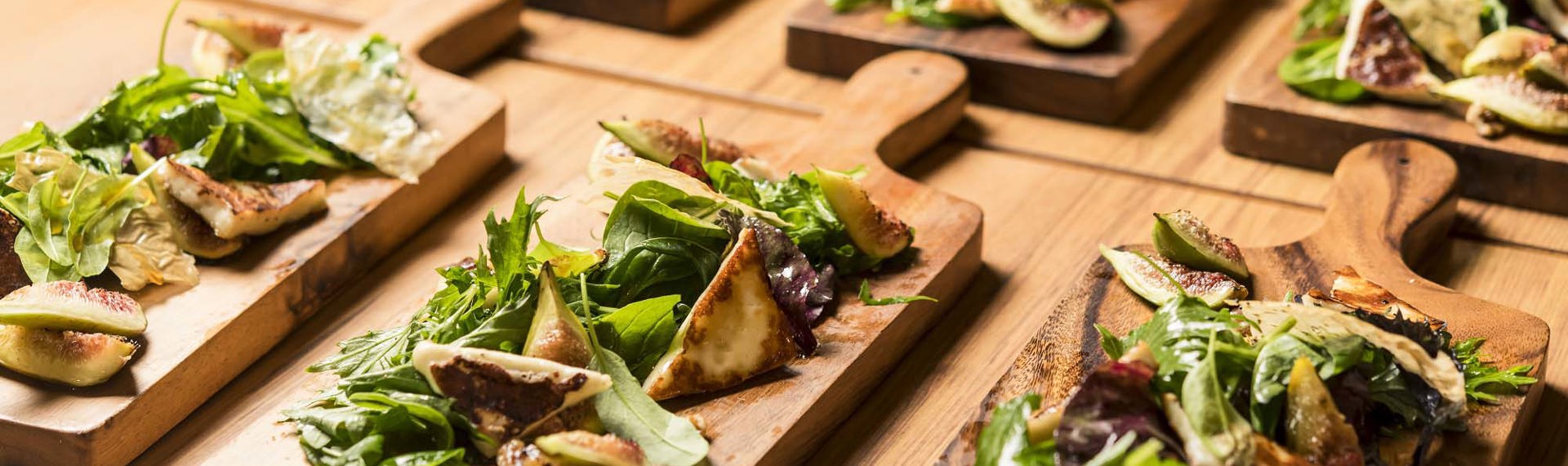 Honey drizzled fig and halloumi salad small plate dishes on wooden chopping boards at the Furneaux Lodge Restaurant in the Marlborough Sounds at the top of New Zealand's South Island