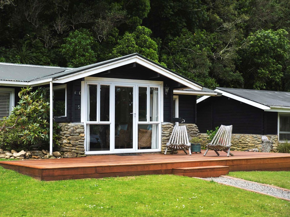 A Cook's Cottage exterior with private deck and outdoor seating at Furneaux Lodge in the Marlborough Sounds at the top of New Zealand's South Island.