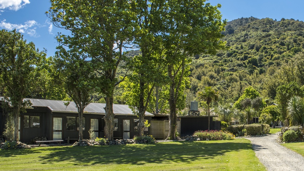 Hiker's Cabins surrounded by tall trees at Furneaux Lodge in the Marlborough Sounds, New Zealand.