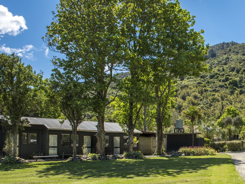 Hiker's Cabins surrounded by tall trees at Furneaux Lodge in the Marlborough Sounds, New Zealand.