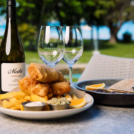 A plate of fish and chips and wine served at Furneaux Lodge in the Marlborough Sounds, New Zealand.