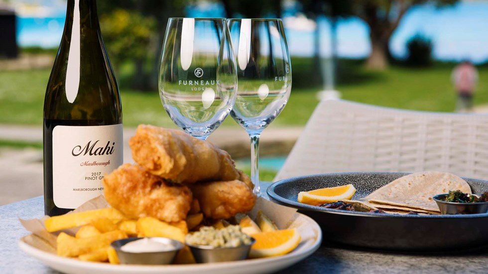 A plate of fish and chips and wine served at Furneaux Lodge in the Marlborough Sounds, New Zealand.