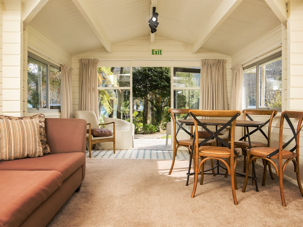 A Cook's Cottage lounge and dining area looking out over the Furneaux Lodge grounds at Furneaux Lodge in the Marlborough Sounds, New Zealand.