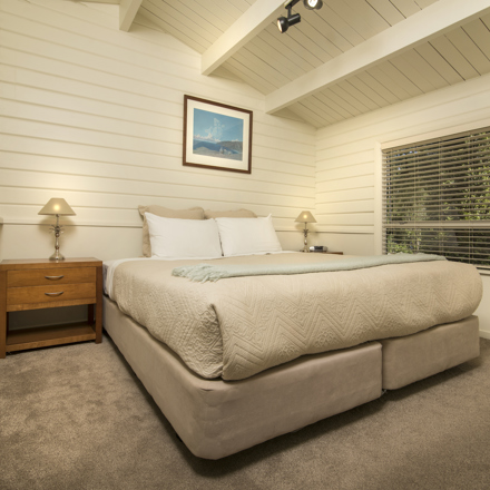 A Cook's Cottage bedroom with a king bed at Furneaux Lodge in the Marlborough Sounds, New Zealand.