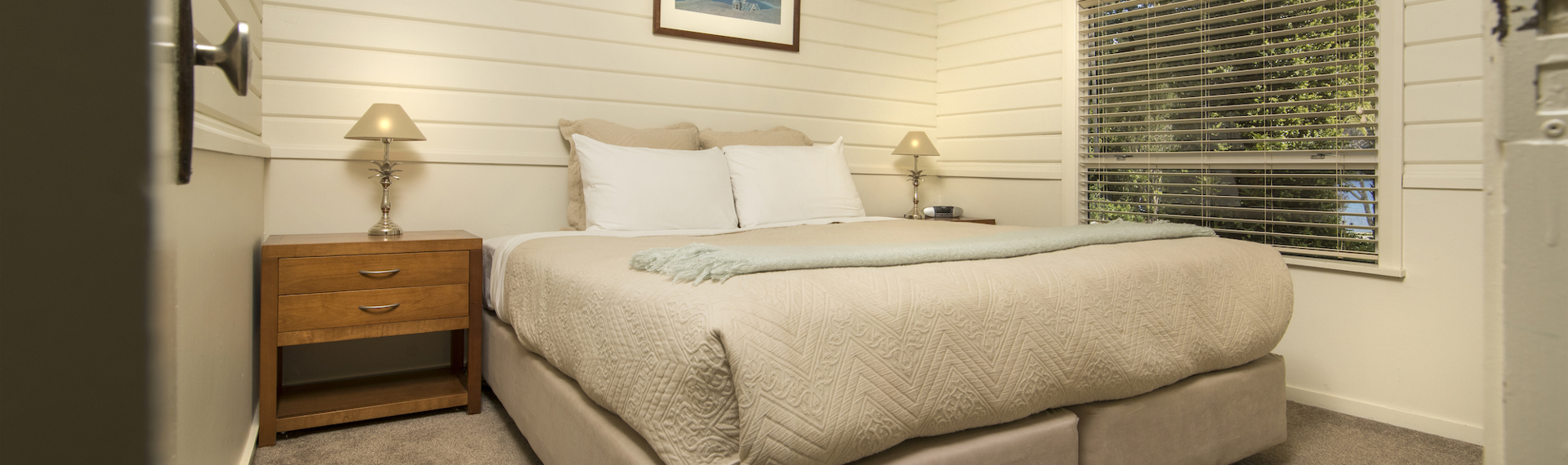 A Cook's Cottage bedroom with a king bed at Furneaux Lodge in the Marlborough Sounds, New Zealand.