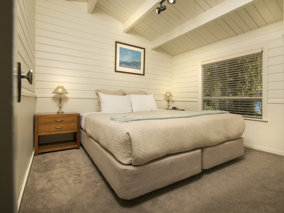 A Cook's Cottage bedroom with a king bed at Furneaux Lodge in the Marlborough Sounds, New Zealand.