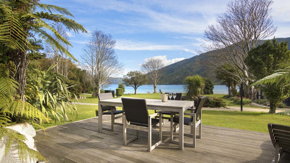 An outdoor dining table on a private Cook's Cottage deck overlooking the Endeavour Inlet Bay at Furneaux Lodge in the Marlborough Sounds at the top of New Zealand's South Island.