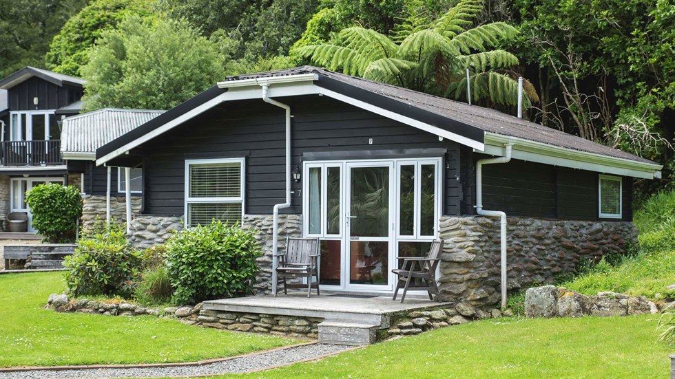 A Cook's Cottage surrounded by lush green native bush at Furneaux Lodge in the Marlborough Sounds at the top of New Zealand's South Island.