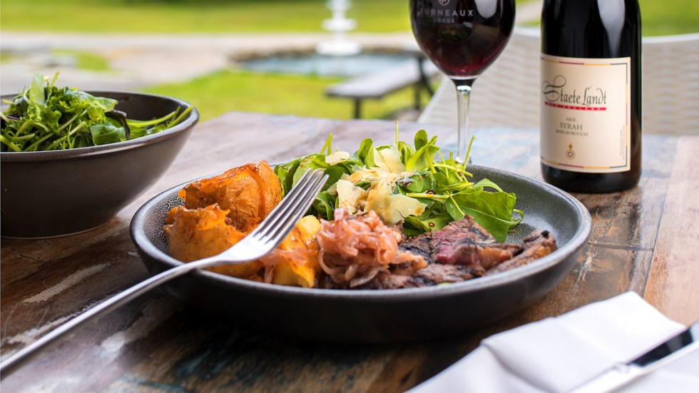 Gourmet steak, potato and salad meal served with ocean view and glass of Staete Landt Syrah at the Furneaux Lodge Restaurant in the Marlborough Sounds at the top of New Zealand's South Island.
