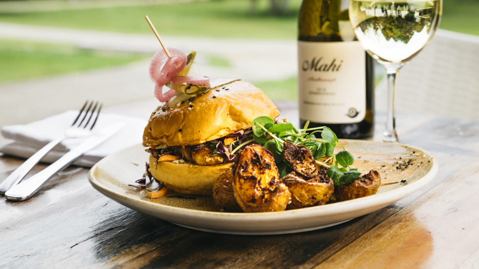 Gourmet chickpea and pumpkin burger with potatoes served with a glass of Mahi Sauvignon Blanc at the Furneaux Lodge Restaurant in the Marlborough Sounds at the top of New Zealand's South Island.