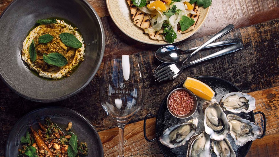 Sharing plate options include gourmet hummus dish, roasted carrots dish, bowl of oysters, open tacos at the Furneaux Lodge Restaurant in the Marlborough Sounds at the top of New Zealand's South Island.